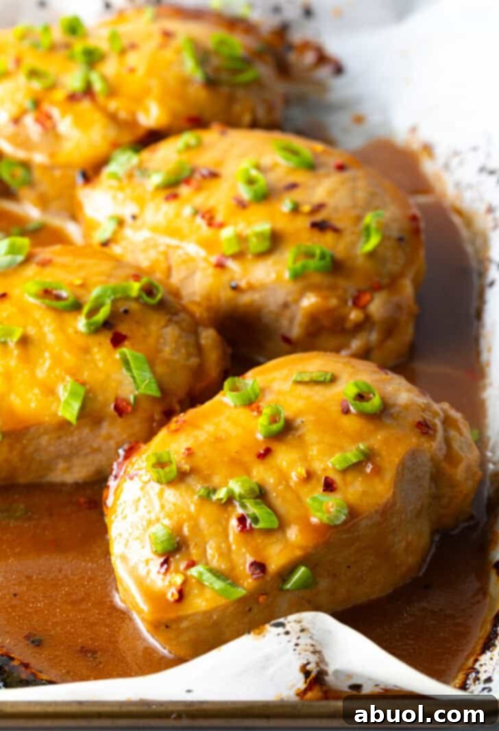 Perfectly Baked Pork Chops 9 A baking sheet filled with perfectly glazed pork chops, generously sprinkled with fresh green onions, ready to serve.