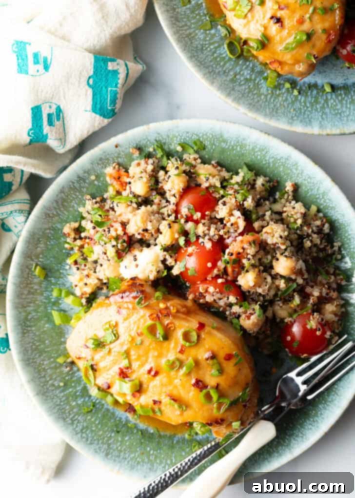 Perfectly Baked Pork Chops 10 A final close-up of a glazed and scallion-topped baked pork chop on a plate next to quinoa salad, with a fork suggesting it's ready to be enjoyed.