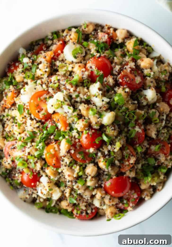 Top down view quinoa salad with cherry tomatoes, chopped fresh herbs, and chickpeas.