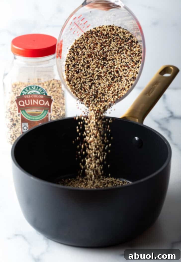 Pouring soaked quinoa from a measuring container into a large black saucepot.