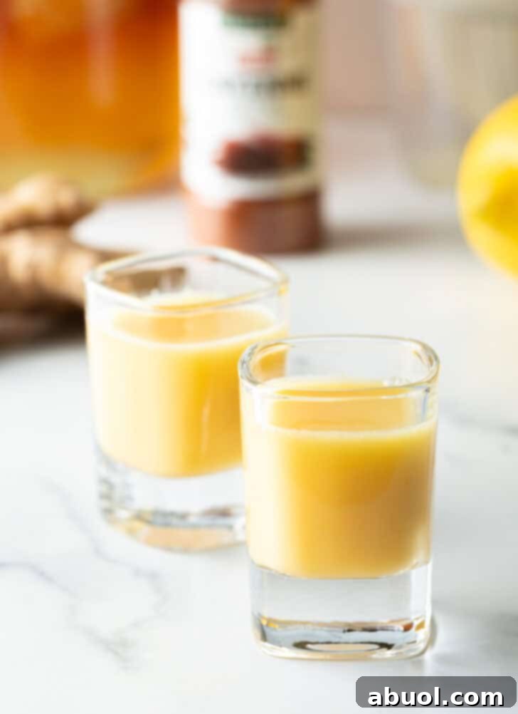 Two shot glasses filled with vibrant yellow ginger shots liquid, ready to be consumed.