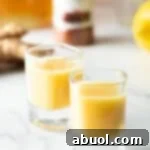 Two shot glasses with yellow ginger shots liquid, ready to drink.