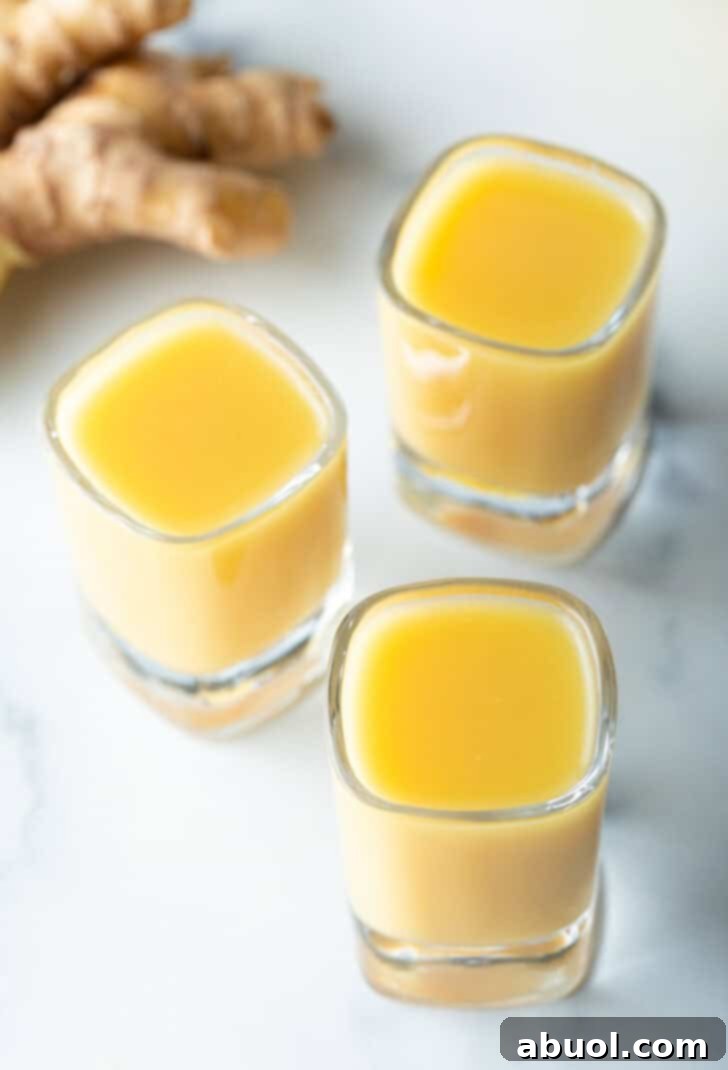 Top-down view of three shot glasses, one with ginger and two with turmeric, showcasing their vibrant colors.