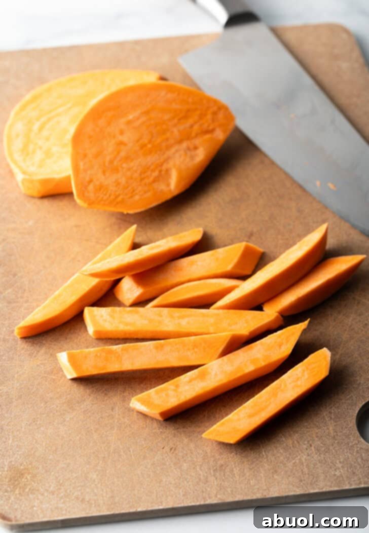 Slicing fresh raw sweet potatoes with a large knife.