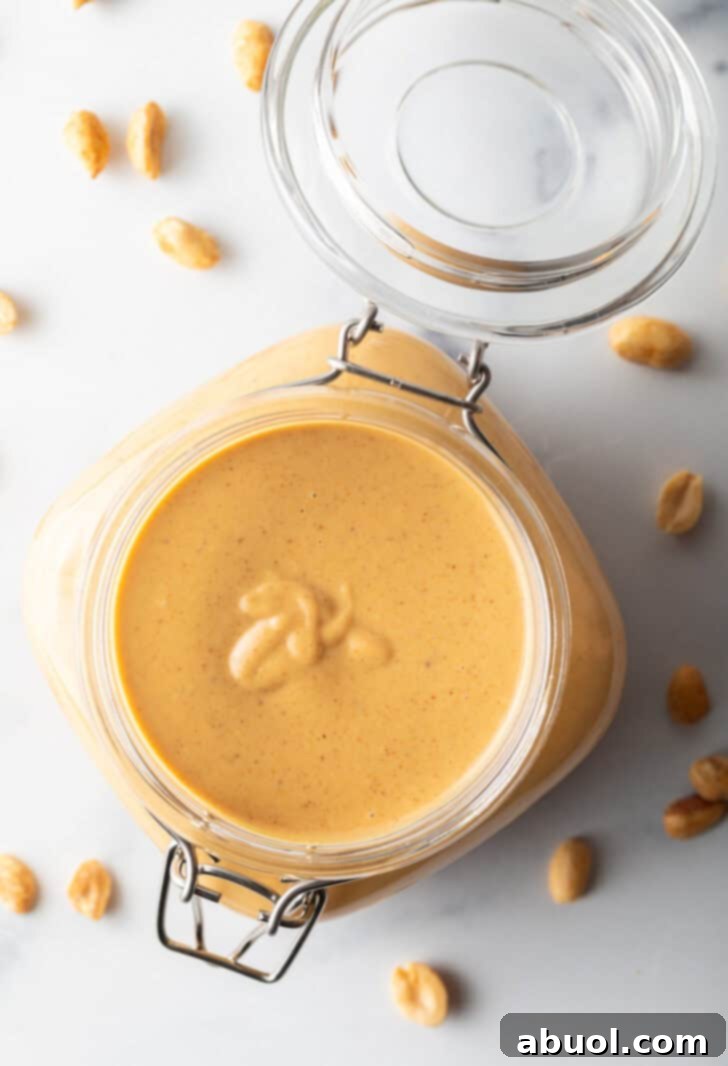 Top-down view of a glass container filled with freshly made homemade peanut butter, highlighting its rich color and smooth texture.