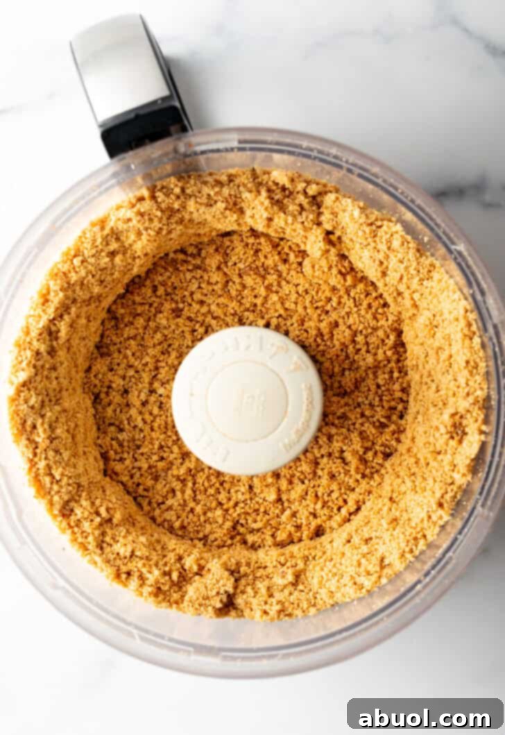 Peanuts starting to blend into a coarse crumb in a food processor.