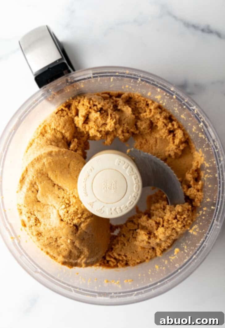Peanuts transforming into a chunky, slightly creamy butter in a food processor.
