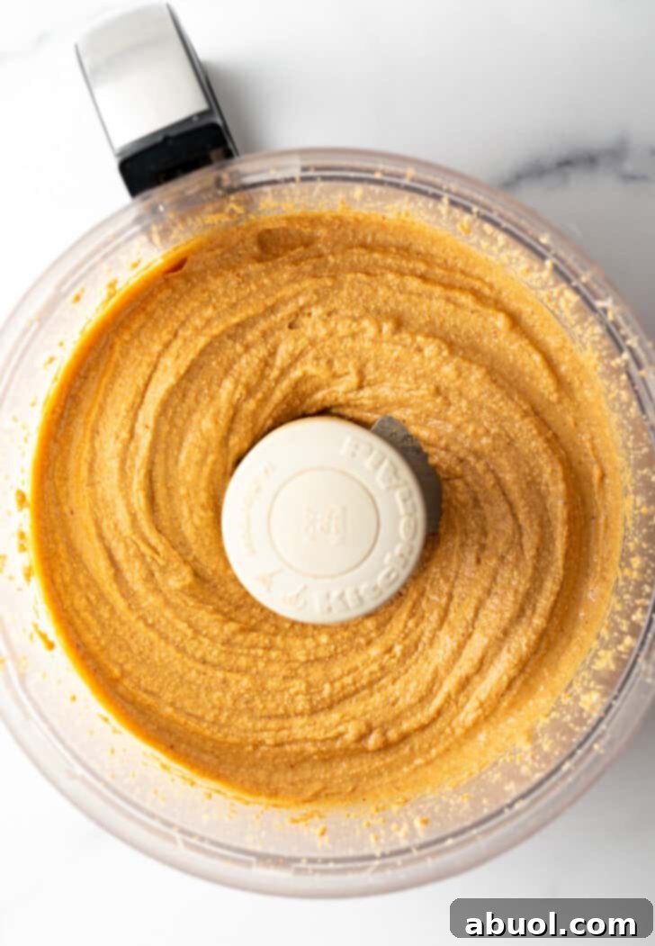 Peanut butter reaching a smoother, still slightly textured stage in a food processor.