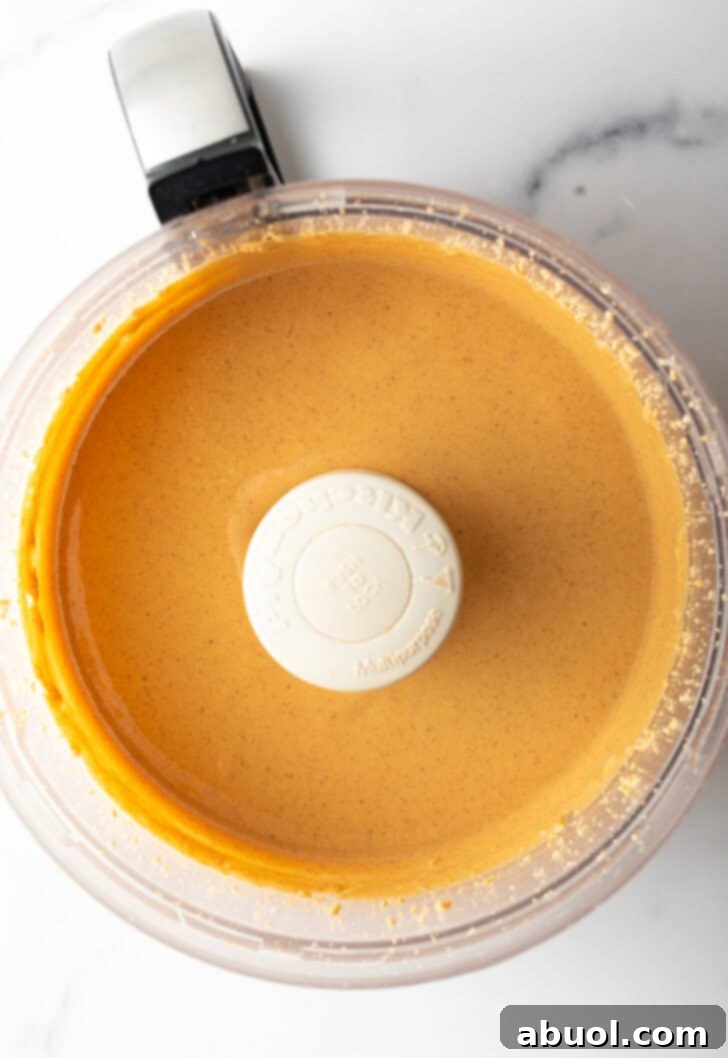 Perfectly smooth and glossy peanut butter swirling in a food processor, ready to be stored.