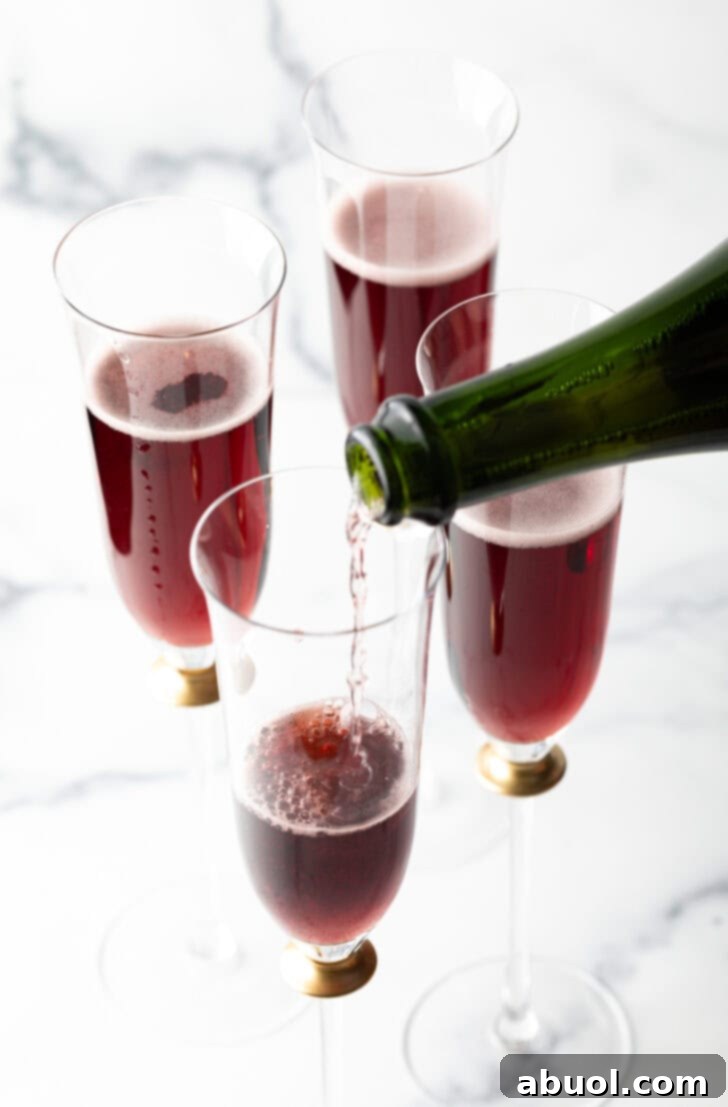 Pouring champagne into a fluted glass with red creme de cassis.