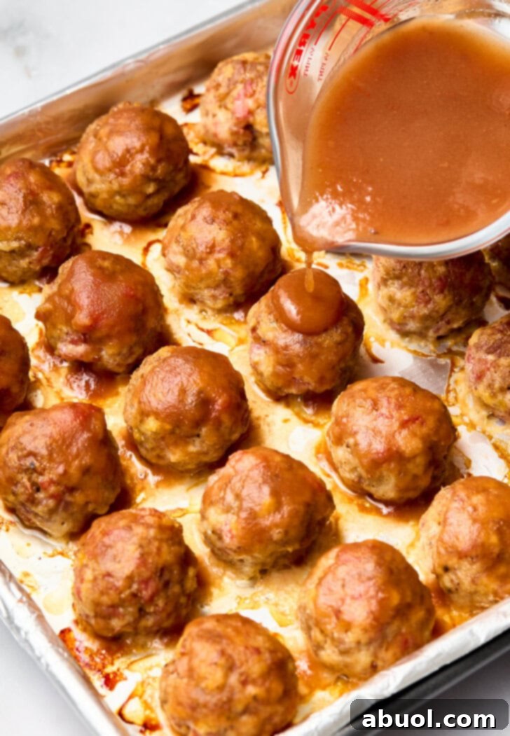 Glazing Spiced Apple Cocktail Meatballs Pouring apple glaze over baked meatballs