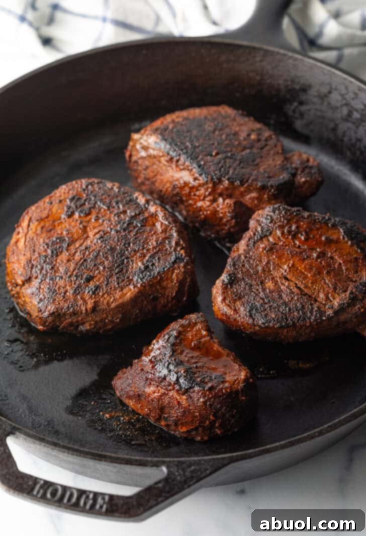 4 filets searing in a cast iron skillet.