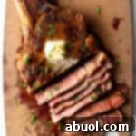 Ribeye steak on a cutting board. Half of the meat has been cut into slices, showing the medium rare inside.