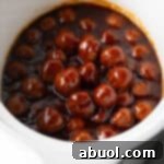 White slow cooker filled with meatballs in bbq sauce.