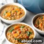 A beautiful bowl of homemade lentil soup with carrots and kale, garnished and ready to eat.