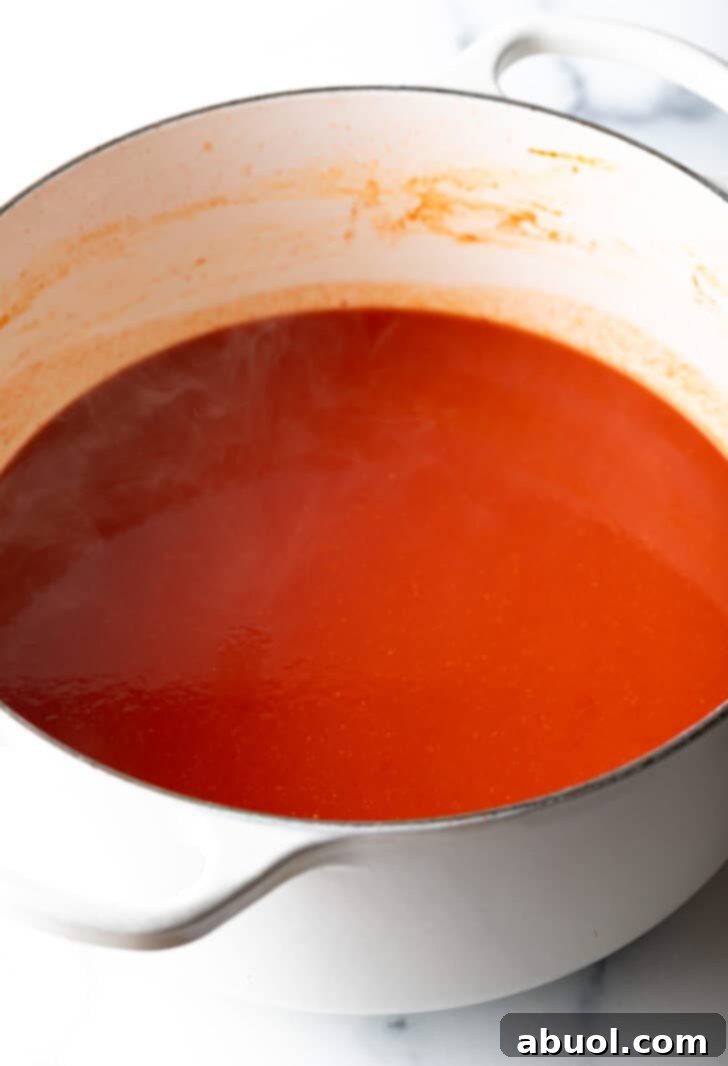 Rich red tomato sauce settling at the bottom of a pristine white cooking pot, ready for the next steps in soup preparation.