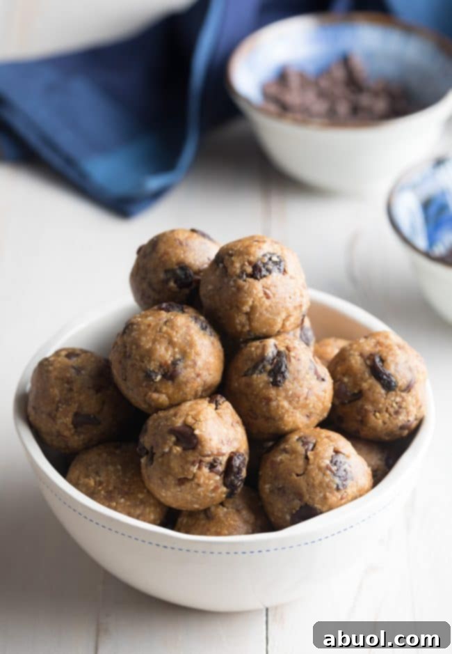 A pristine white bowl filled to the brim with delicious oatmeal energy balls, each speckled with rich peanut butter, dark chocolate chips, and plump raisins, ready to be enjoyed.