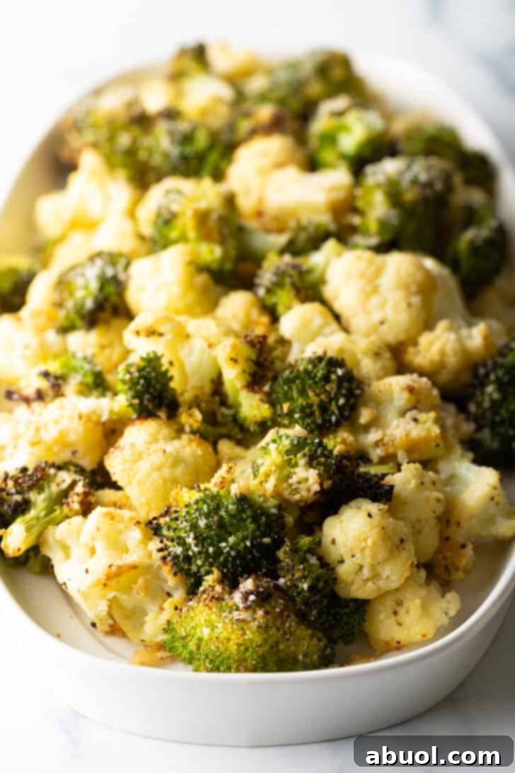 A white oval platter loaded with golden-brown, tender, and crispy roasted broccoli and cauliflower florets, ready to be enjoyed as a side dish.