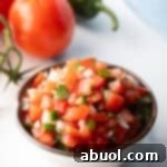 A white bowl of fresh pico de gallo with chopped tomatoes, onion, jalapeno, and cilantro, a delicious and fresh appetizer.