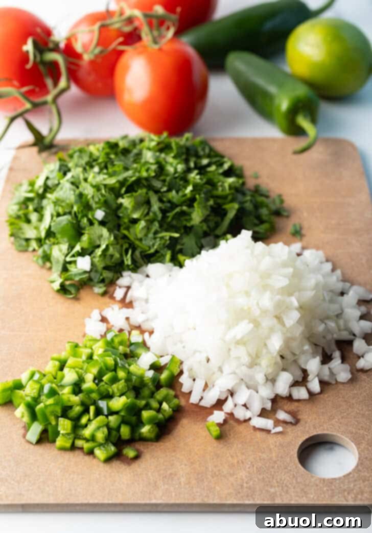 Recipe ingredients in separate piles on a cutting board: Fresh chopped cilantro, jalapenos, and onion, perfectly prepped.