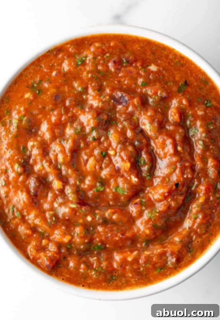 Top down view of a white bowl of red roasted tomato salsa.