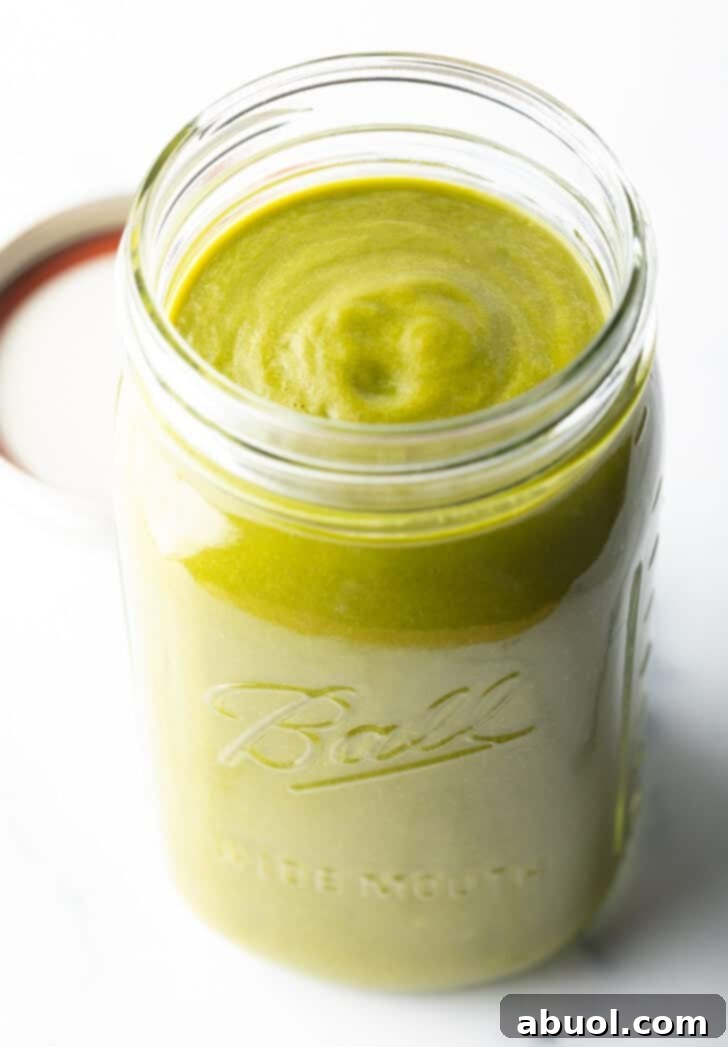 Large glass mason jar filled with bright green enchilada sauce, ready for storage or serving.