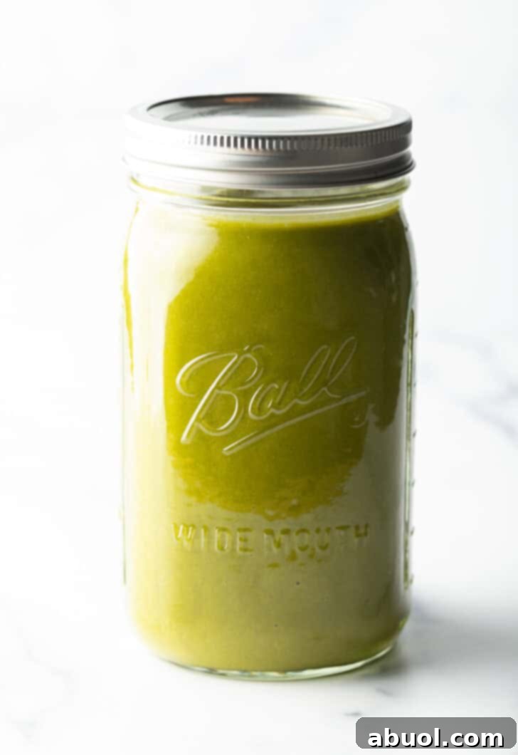 A large glass mason jar brimming with smooth, homemade green enchilada sauce, ready for serving or storing.
