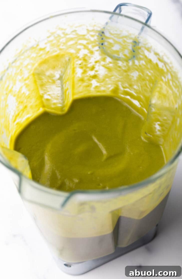 Smooth, bright green poblano sauce swirling in a blender, ready to be poured.