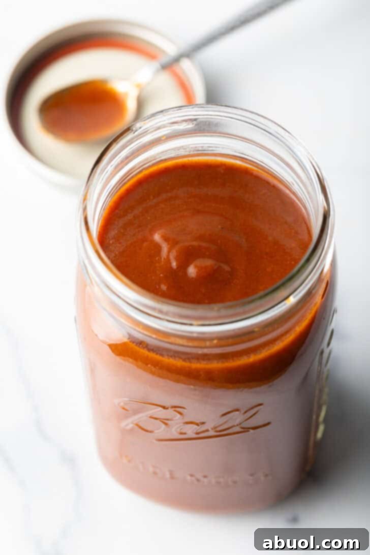 Top down view of red sauce in a large glass jar.