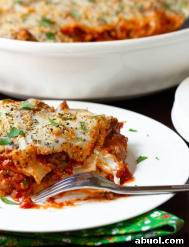 Italian sausage Lasagna on plate with a bite taken out, showing the layers.