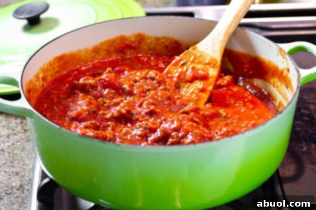 Sausage and tomato sauce simmering for lasagna with cream cheese