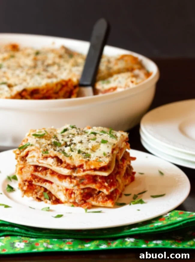 Easy lasagna recipe with cream cheese served on a white plate with a fork.
