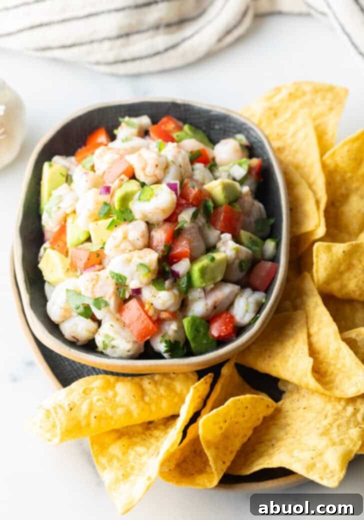 Top down view yellow bowl with shrimp ceviche. The bowl is surrounded by tortilla chips.