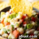 Yellow bowl of shrimp ceviche with a tortilla chip sticking in the middle.