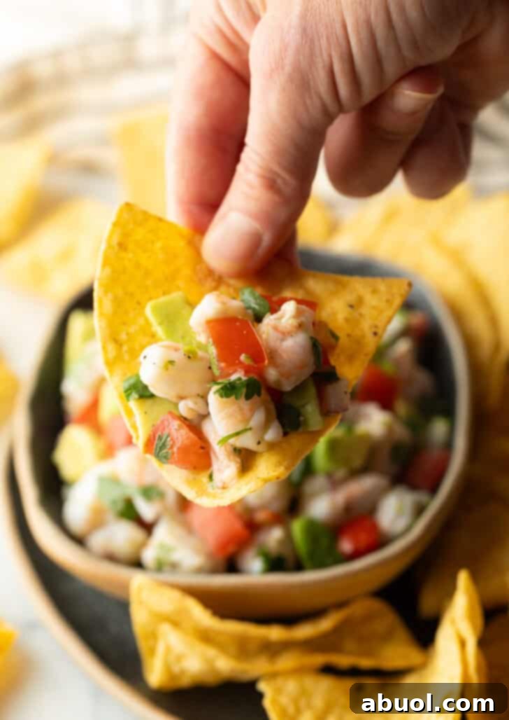 How to Make Shrimp Ceviche - Hand showing a scoop of ceviche on a tortilla chips held to camera.