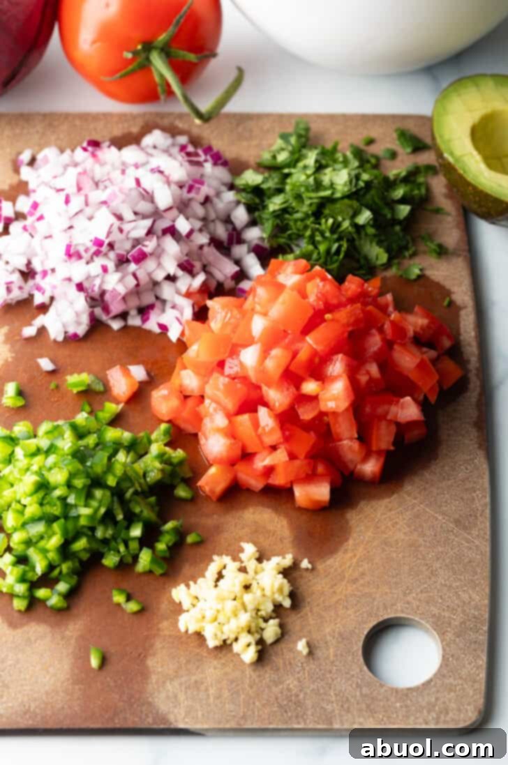 Recipe ingredients: Piles of chopped red peppers, green peppers, garlic, red onion, and cilantro.