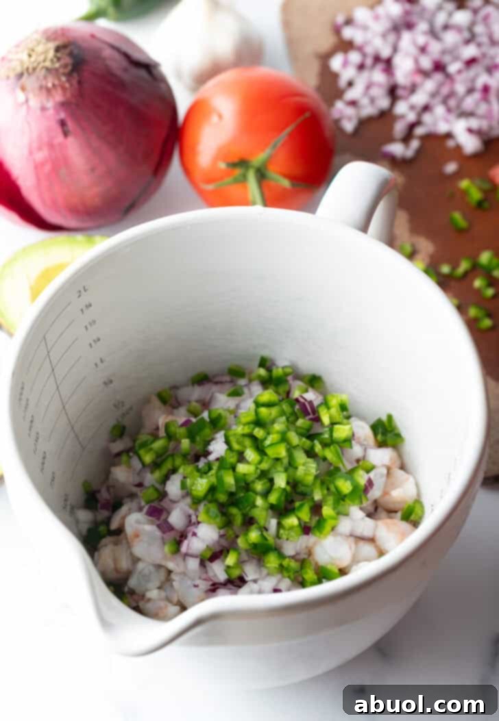 White bowl with raw shrimp and peppers on top.