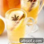 Crafting a Cozy Hot Toddy 12 2 glass handled mugs with hot toddy, garnished with star anise and a cinnamon stick.