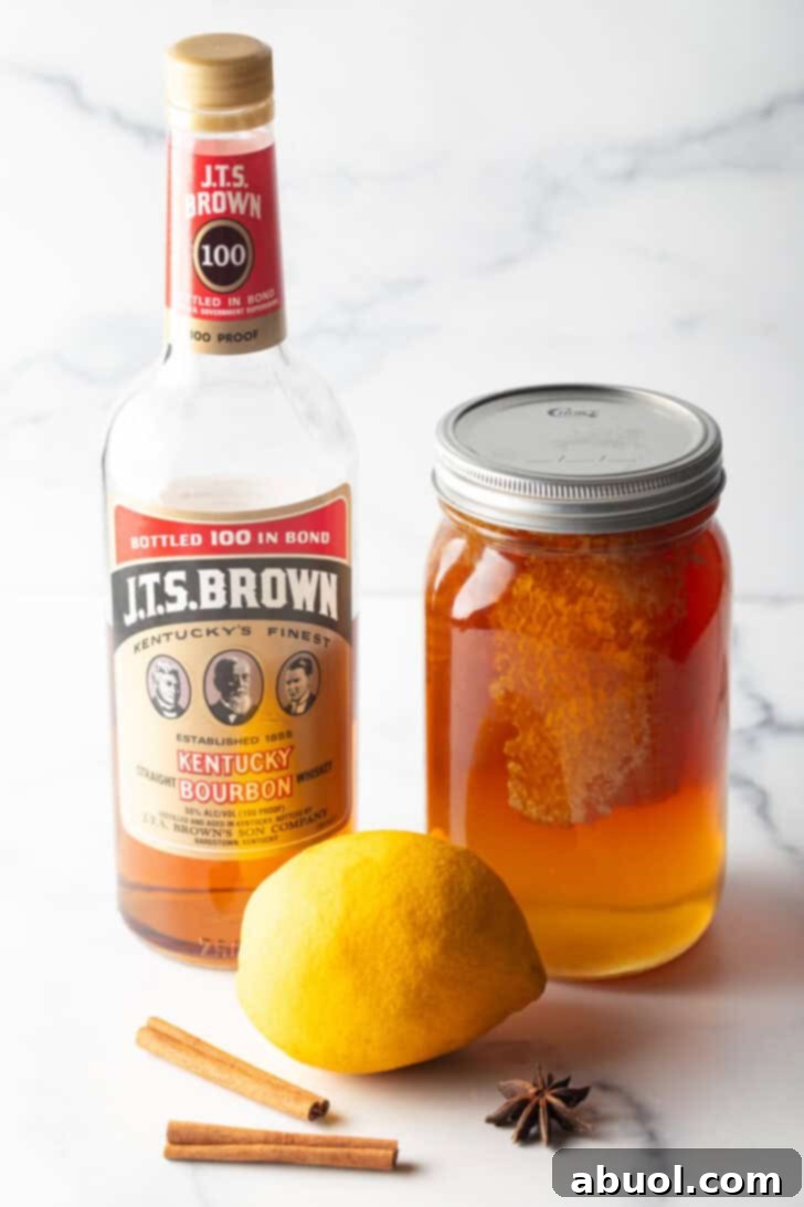 Crafting a Cozy Hot Toddy 5 Recipe ingredients together: large mason jar of honey, whole lemon, and bottle of bourbon.