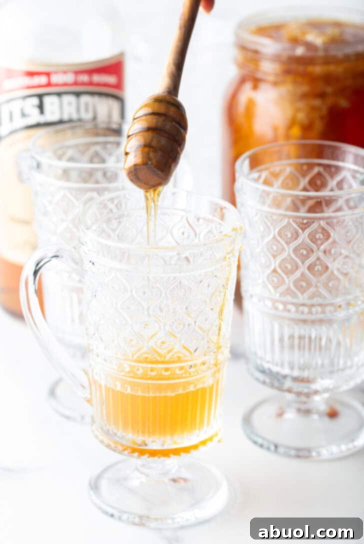 Crafting a Cozy Hot Toddy 8 Adding honey to a clear handled mug.