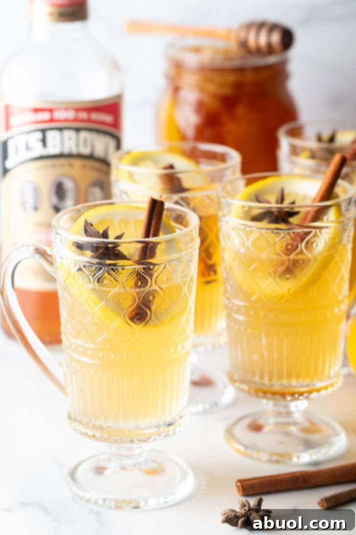 Crafting a Cozy Hot Toddy 10 3 glasses with yellow tea, garnished with a whole star anise and stick of cinnamon.