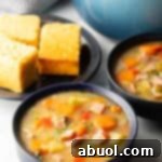 Two black bowls of ham and cabbage soup next to a black plate with 3 squares of cornbread.