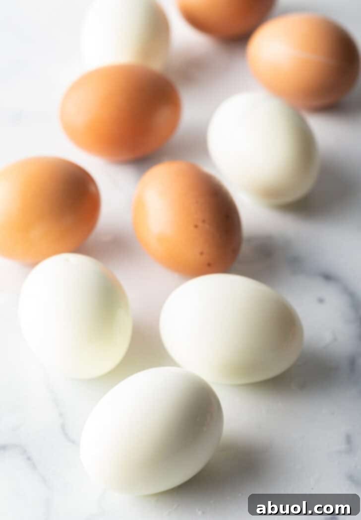 A top-down perspective showcasing four peeled hard-boiled eggs alongside three brown unpeeled eggs, demonstrating successful peeling and serving readiness.