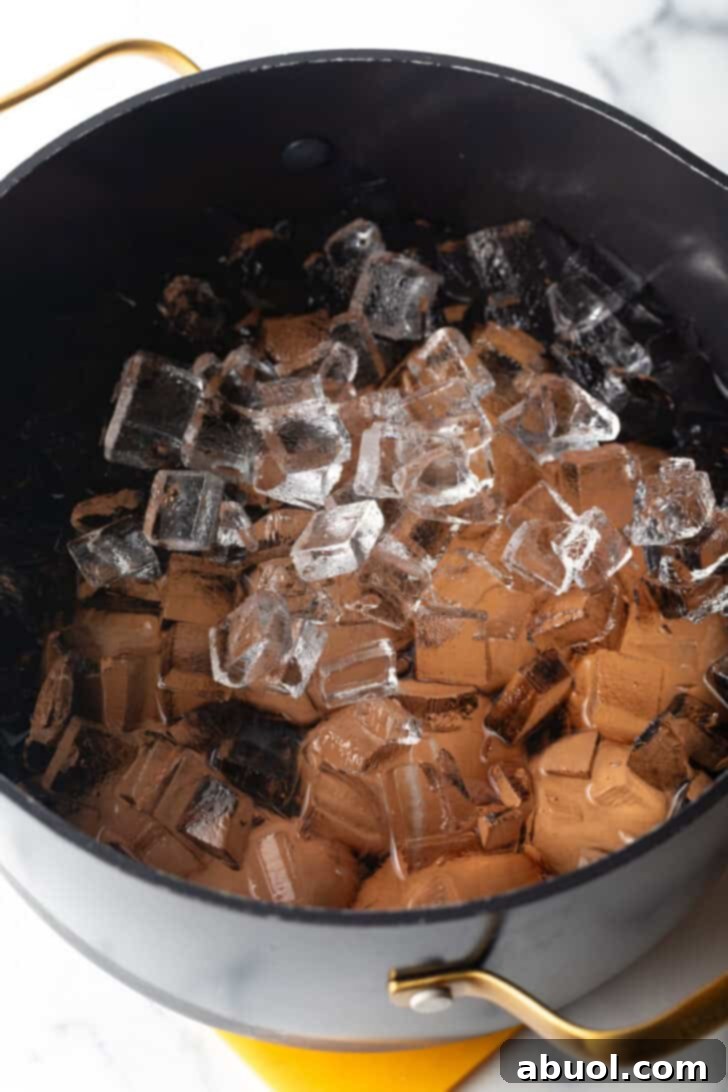 A large black pot of hard-boiled eggs covered generously with ice cubes, illustrating the crucial ice bath step to stop cooking.