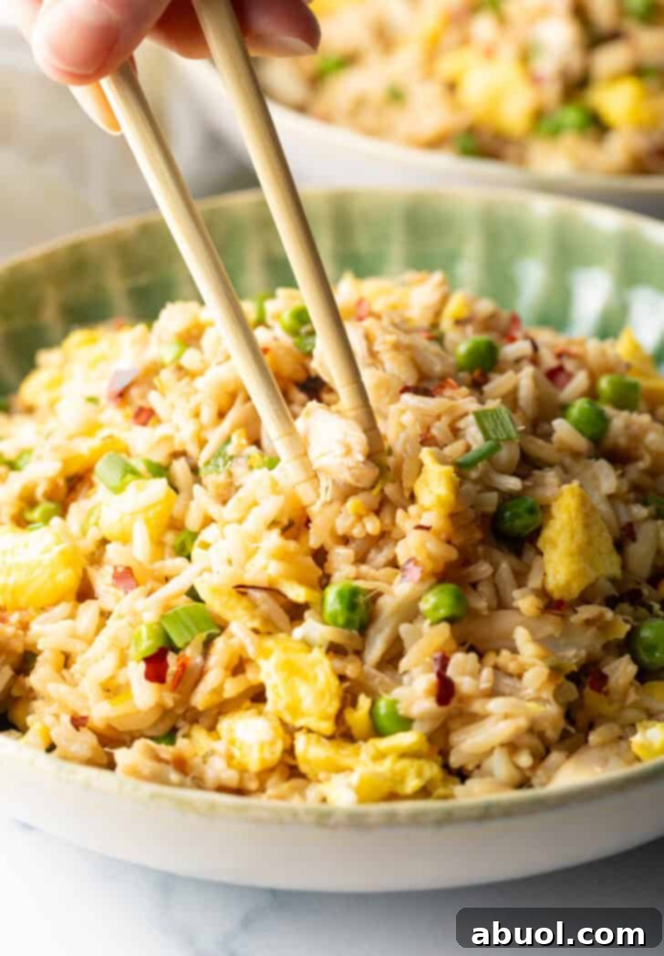 Fragrant Thai Crab Fried Rice 2 Chopsticks holding a bite of fried rice with crab, taking it from a plate of the rice.
