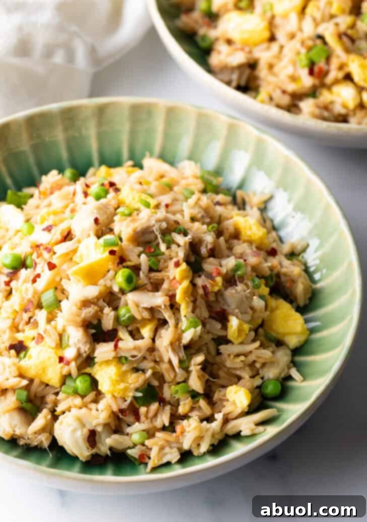 Fragrant Thai Crab Fried Rice 5 Top down view of a green plate with crab fried rice with chunks of crab meat and peas.