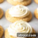 Several honey butter cornbread cookies on a white background, each topped with piped frosting.