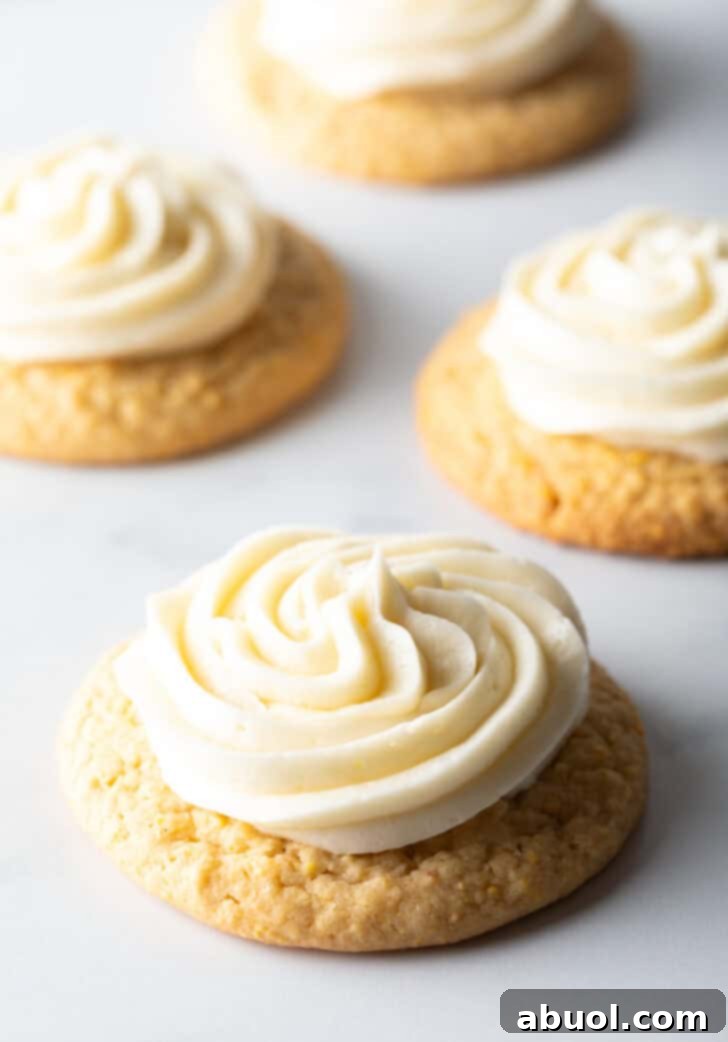 Several honey butter cornbread cookies on a white background, each topped with piped frosting.