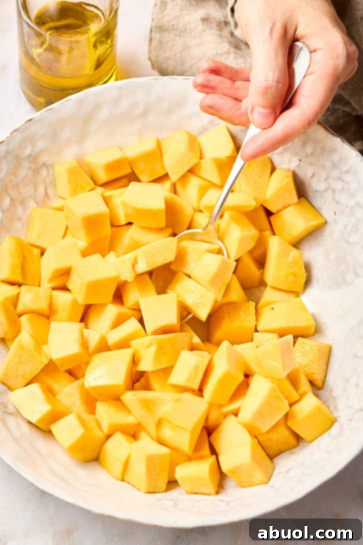 Diced butternut squash in a bowl, coated in oil, ready for roasting.