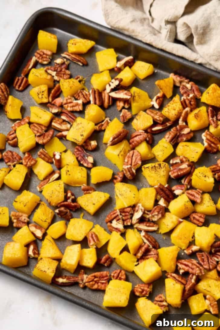 A baking sheet with roasted acorn squash and pecans, golden and caramelized.